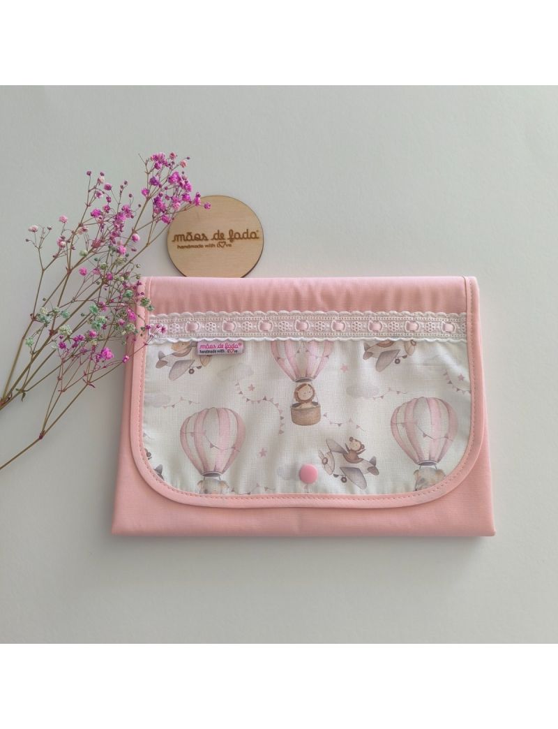 Muda fralda fechado com tecido rosa conjugado com padrão de balões de ar quente e aviões em tons suaves. Com bordado inglês com fita rosa 