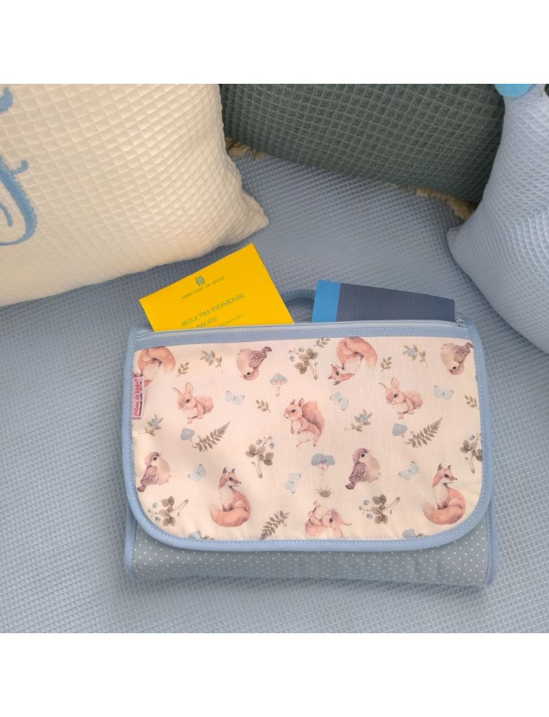 Bolsa multiusos fechada com uma bolsa frontal. Padrão de animais da floresta conjugado ciom um tecido azul com pintinhas brancas. Fecho zíper azul