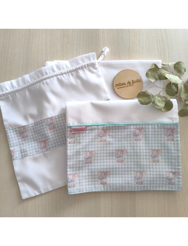 Lençol de cima, lençol de baixo e saquinho. O lençol de cima e o saquinho possuem uma barra com padrão de quadradinhos verde água e brancos com uns amorosos elefantes em tons de cinzento