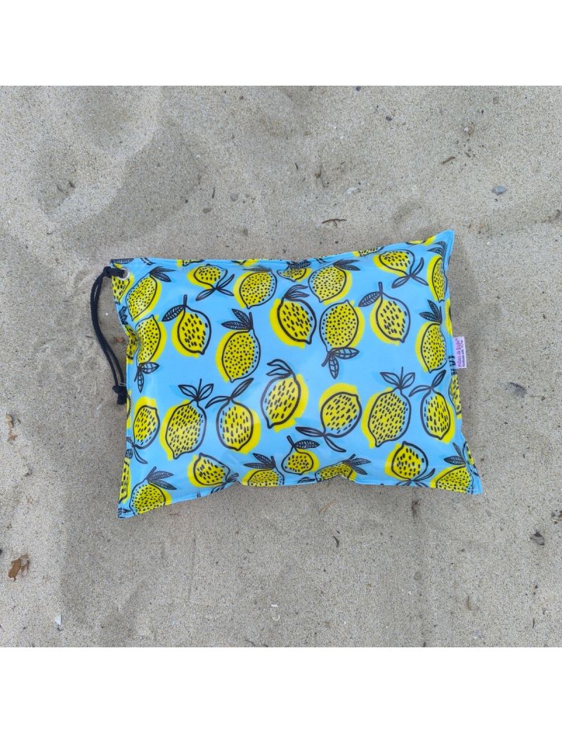 Almofada de praia com o fundo azul claro com padrão de limoes amarelos com contorno em azul escuro. Alça em azul escuro 