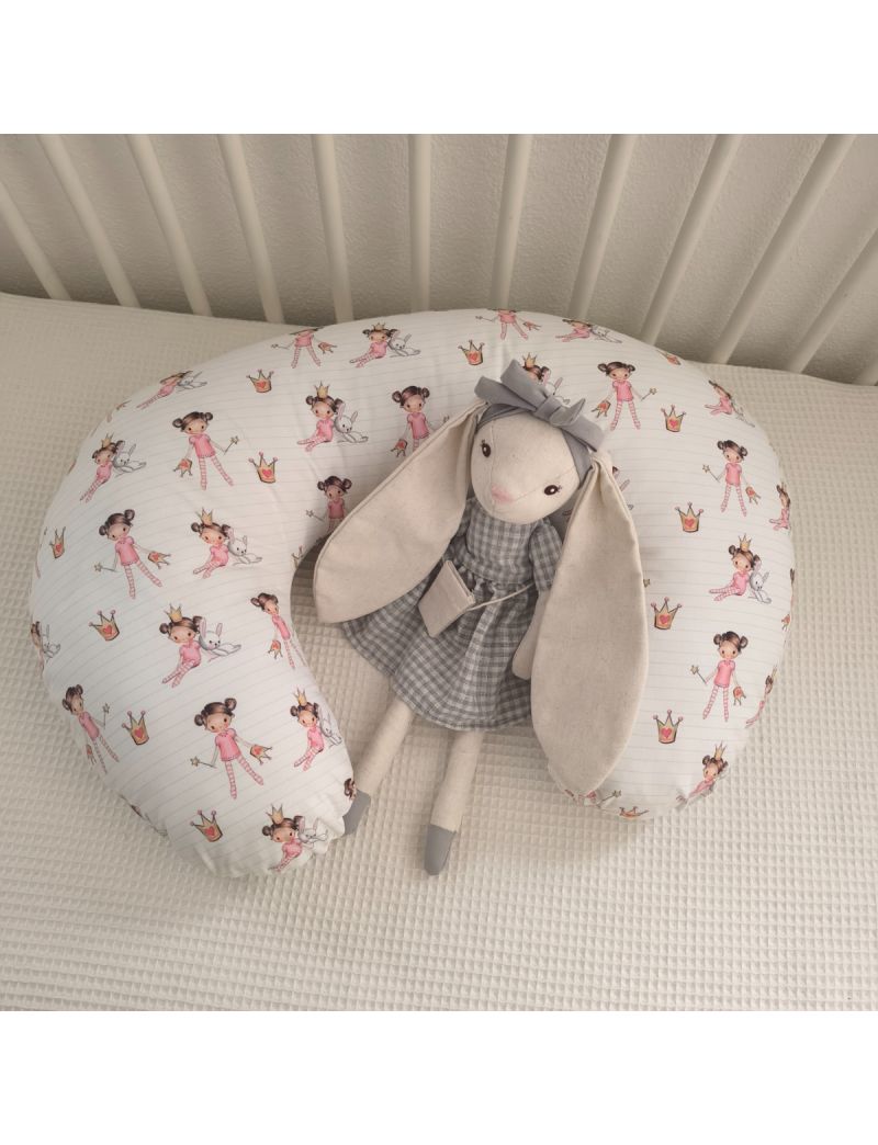 Almofada de amamentação com padrão de bonequinhas colocada dentro de uma cama de grades branca. Coelhinda na decoração 