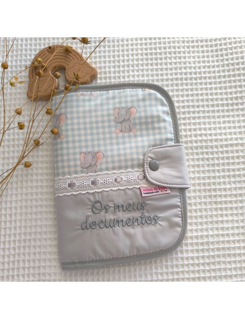 Porta documentos em formato livro com padrão de elefantes em cima de tecido xafrez vichy verde água conjugado com tecido liso cinzento com a descrição "Os meus documentos" a cinzento. Bordado inglês na junção dos dois tecidos com fita de cetim cinza.