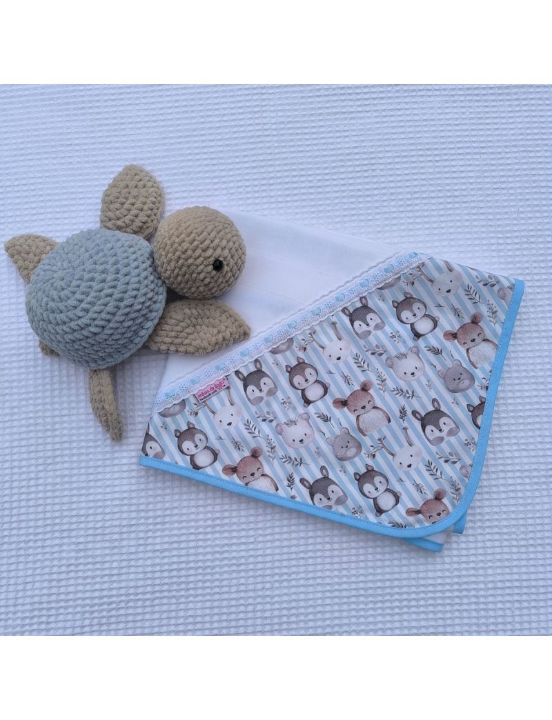 Fralda branca com canto com padrão de animais delicados sobre tecido listrado azul claro e branco. Bordado inglês com fita de cetim azul claro. Tartaruga a decorar 