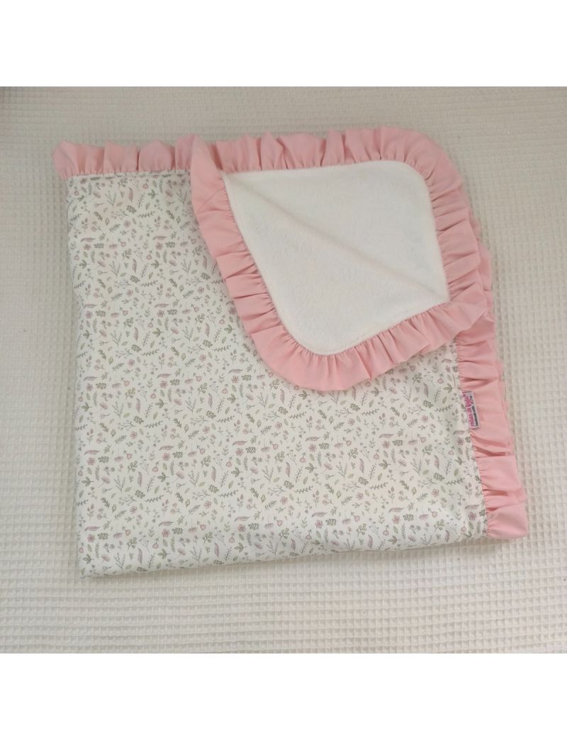 Mantinha de bebé em tecido de algodão com padrão de pequenas flores delicadas rosa no exterior e coralina branca quentinha no interior. Folho cor-de-rosa a contornar a mantinha 