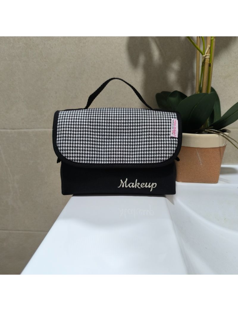 Bolsa de maquilhagem minimalista, preta  e branca, compacta, com alça preta superior.