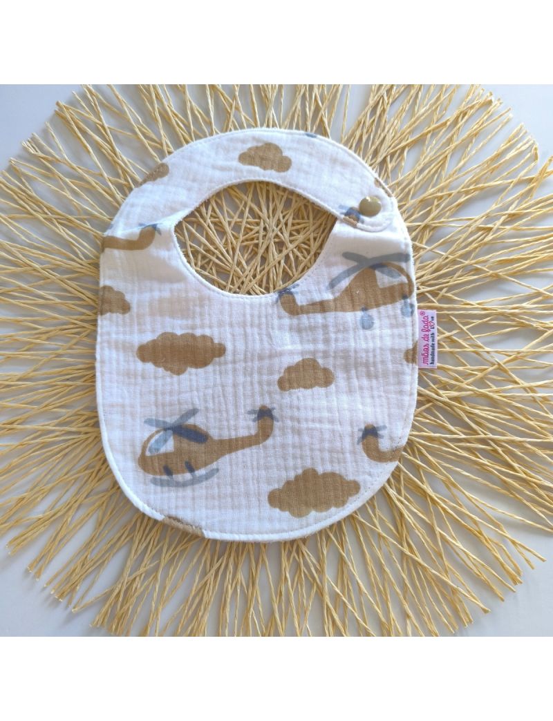 Babete de musselina branca com hilicópteros e nuvens em tons de camel, fecho de mola, ideal para bebés até aos 7 meses