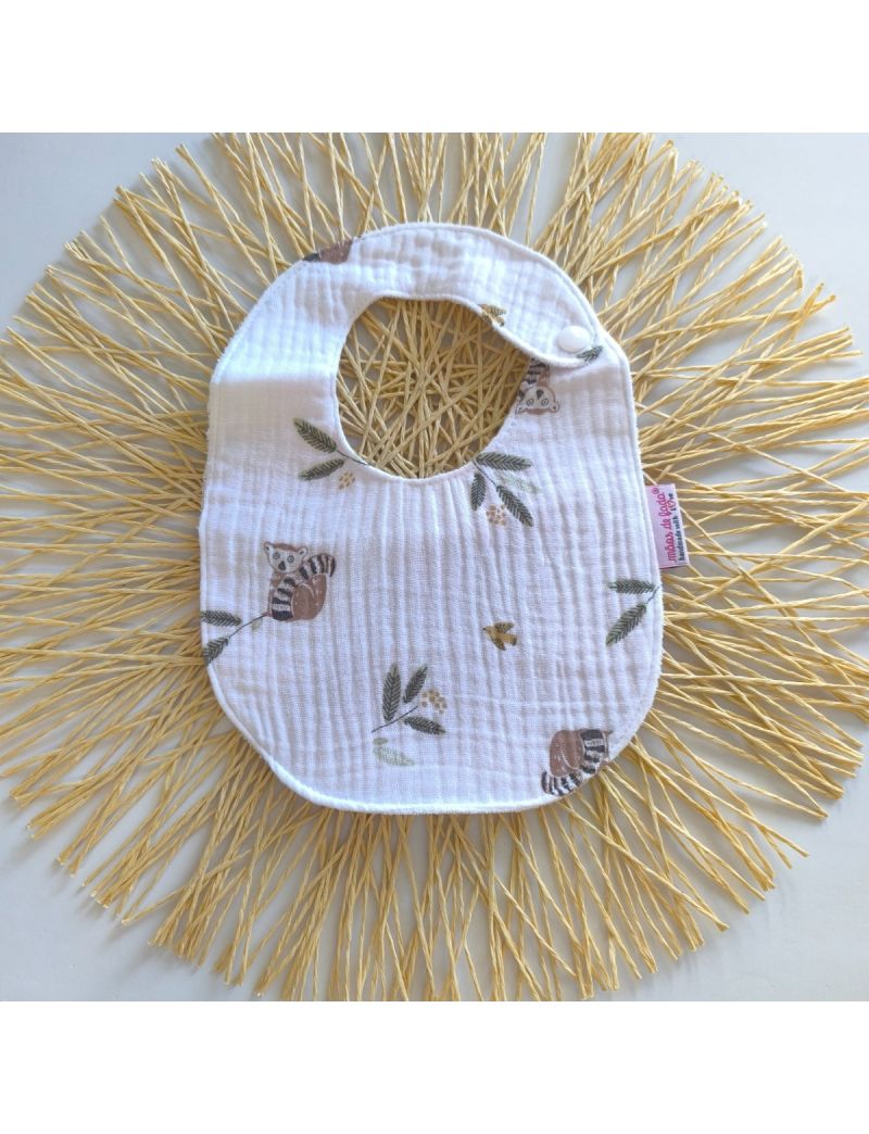 Babete de musselina branca com animais ilustrados, fecho de mola, impermeável, ideal para bebés até aos 7 meses. 