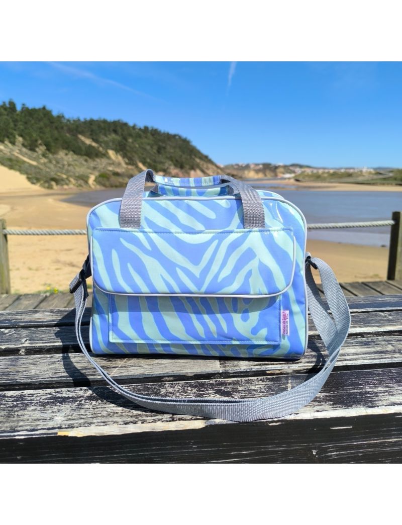 Lancheira t&eacute;rmica  com padr&atilde;o animal print em tons de roxo e verde-&aacute;gua vibrante, destacando a bolsa frontal, as al&ccedil;as de m&atilde;o e a al&ccedil;a a tiracolo ajust&aacute;vel em cinzento-claro.