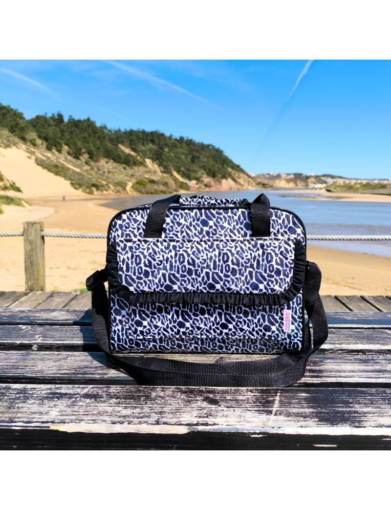 Lancheira t&eacute;rmica com padr&atilde;o preto e branco. A lancheira possui uma bolsa frontal com folho em preto, al&ccedil;as de m&atilde;o refor&ccedil;adas e al&ccedil;a a tiracolo regul&aacute;vel na mesma cor. O acabamento exterior &eacute; plastificado e brilhante.