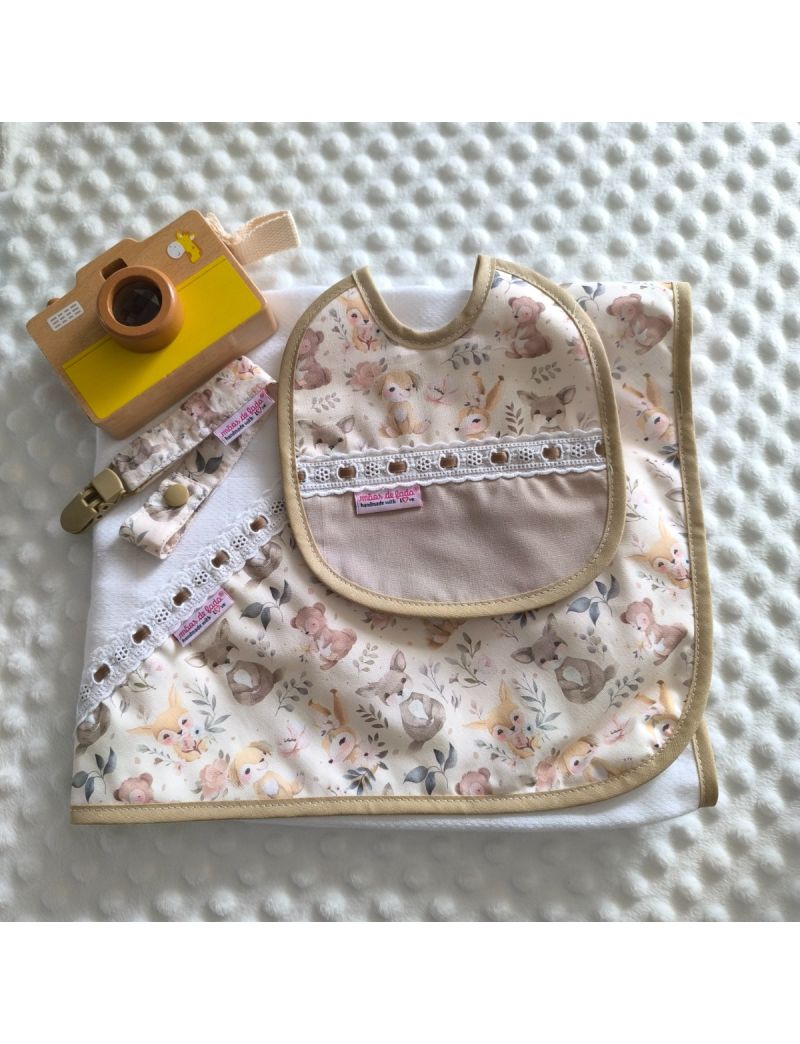 Conjunto de beb&eacute; composto por fralda, babete de atilho e fita para a chucha com fundo bege clarinho e com padr&atilde;o de animais em tons de bege, castanho, rosa e amarelo