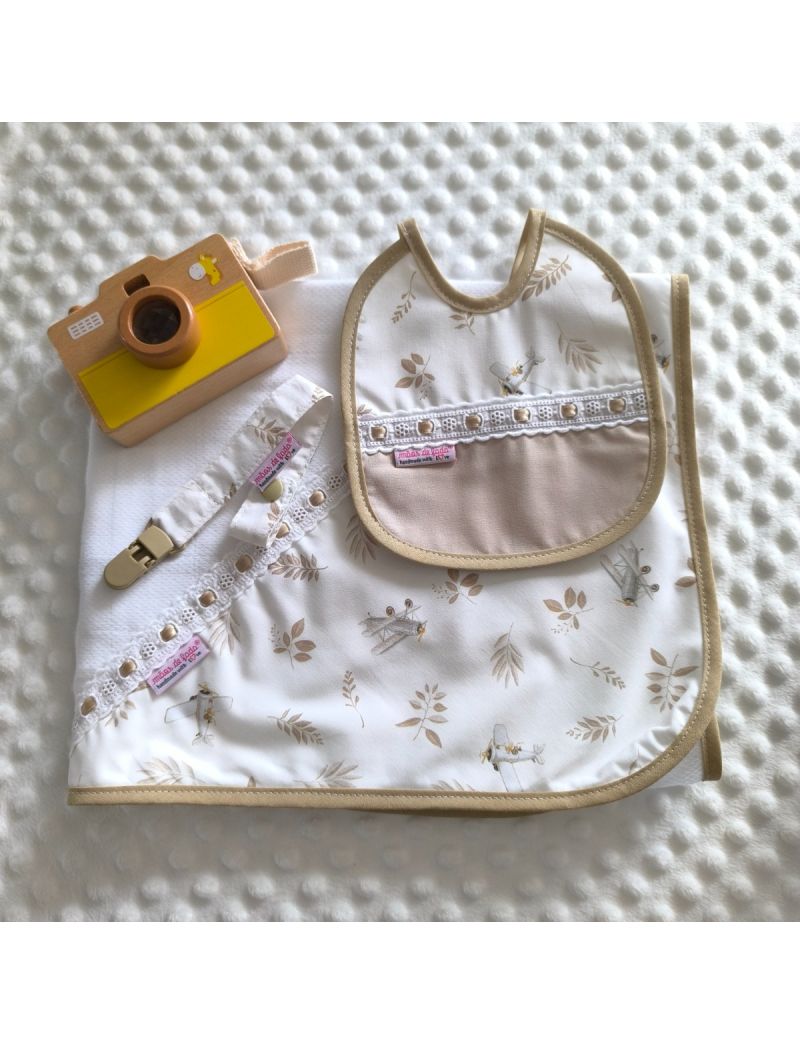 Conjunto de beb&eacute; composto por fralda branca com tri&acirc;ngulo de tecido com padr&atilde;o de delicadas folhas e avionetas em tons de bege. Babete com o mesmo padr&atilde;o conjugado com tecido bege liso e com bordado ingl&ecirc;s com fita de cetim bege. Fita para a chucha com o 