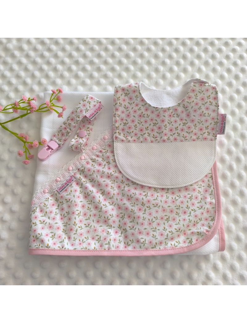 Conjunto de enxoval de beb&eacute; que inclui uma fralda com canto com um padr&atilde;o floral rosa, um babete de mola com o mesmo padr&atilde;o e base em tecido favo de mel branco, e uma fita de chucha coordenada com mola rosa