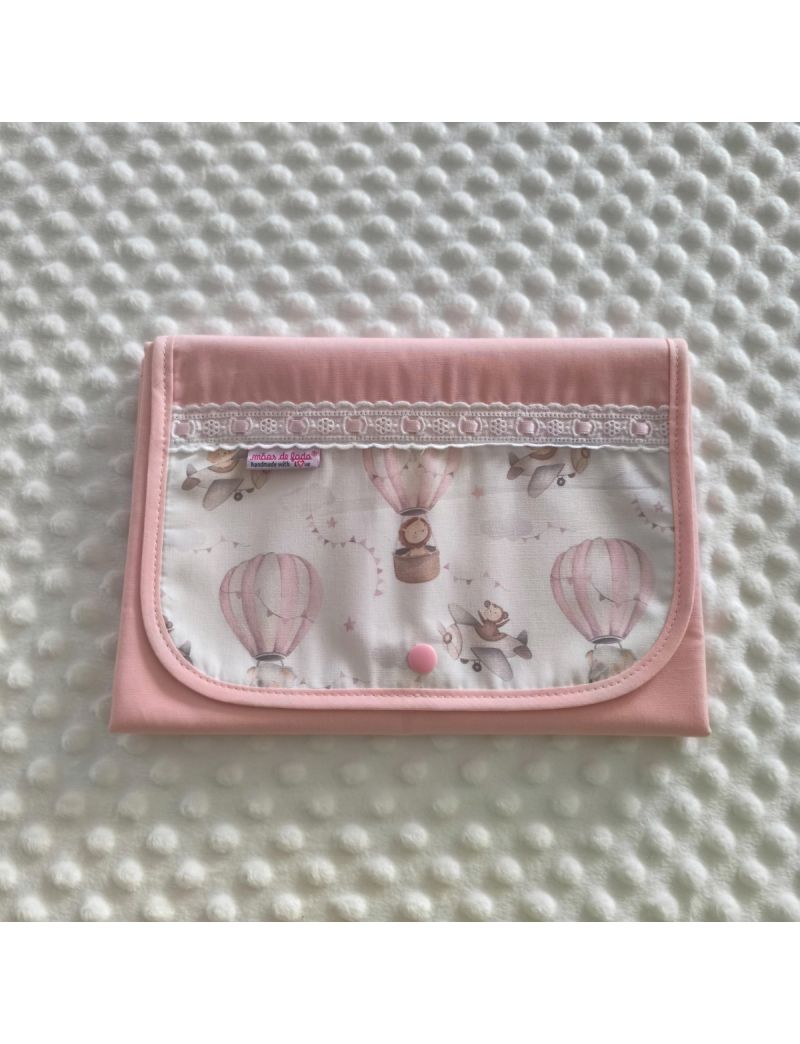 Muda fralda fechado com tecido rosa conjugado com padr&atilde;o de bal&otilde;es de ar quente e avi&otilde;es em tons suaves. Com bordado ingl&ecirc;s com fita rosa 