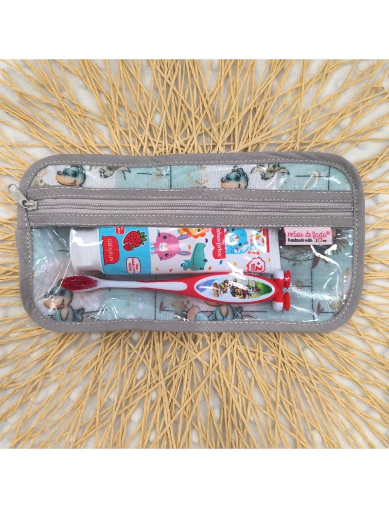 Bolsa de higiene para crian&ccedil;a com fundo verde &aacute;gua com dinossauros. Fecho cinzento. No interior possui uma escova e pasta de dentes como exemplo