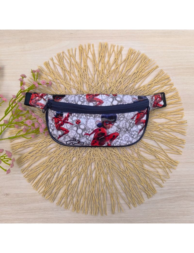 Bolsa de cintura com o padão da Ladybug em tons de vermelho e preto. Fecho e alça em azul escuro 