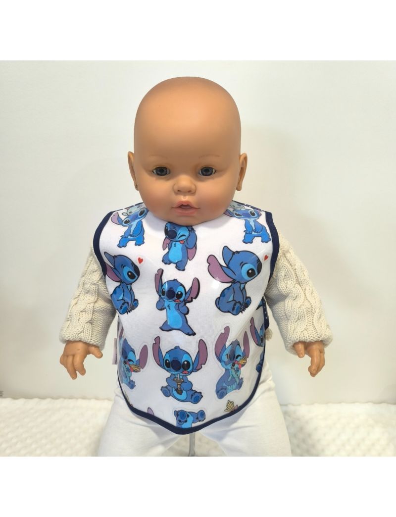 Babete de beb&eacute; plastificado com estampado do personagem Stitch e rebordo azul, colocado sobre camisola de malha clara.