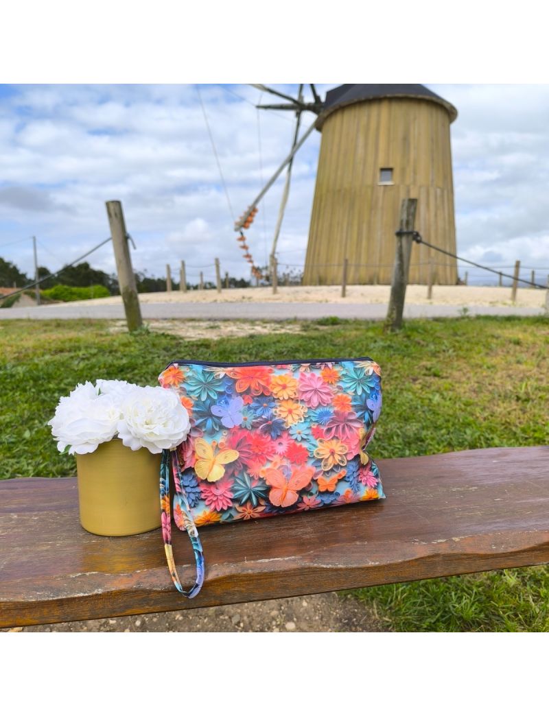 Necessaire em tecido plastificado com padr&atilde;o floral com borboletas que lembra o 3D. Cores vibrantes, tais como azul, amarelo, rosa e laranja