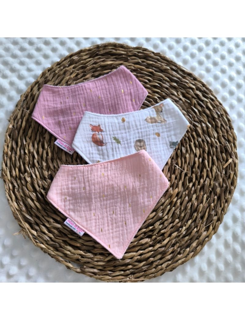 Conjunto de tr&ecirc;s babetes badana em musselina dispostos sobre uma base de verga circular. O pack apresenta um babete central branco com ilustra&ccedil;&otilde;es de raposas, veados e esquilos, ladeado por dois babetes em tons de rosa com pequenos detalhes dourados