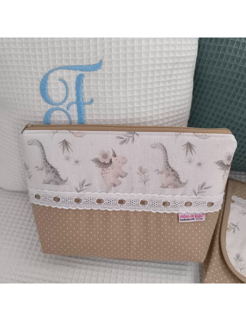 Necessaire bege com pintinhas brancas conjugado com um padrão de dinossauros em tons neutros. Com bordado inglês e fita de cetim bege