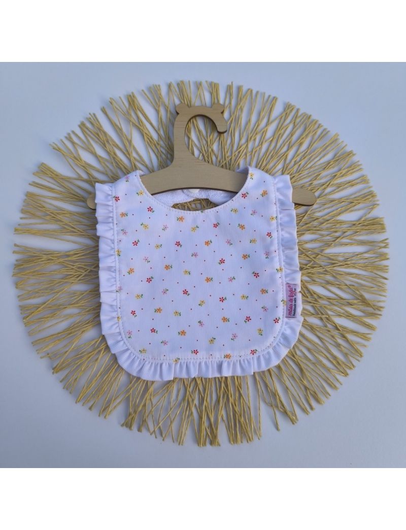 Babete branco com pequenas flores vermelhas rosa e amarelas. Folho branco a contornar o babete 