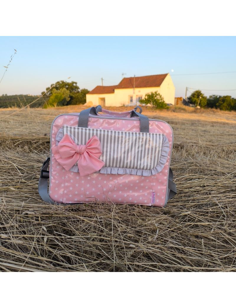 Lancheira térmica em tecido plastificado rosa com estrelas brancas. Com bolso frontal e pala com folho cinza e laço rosa. Ideal para o trabalho ou escola