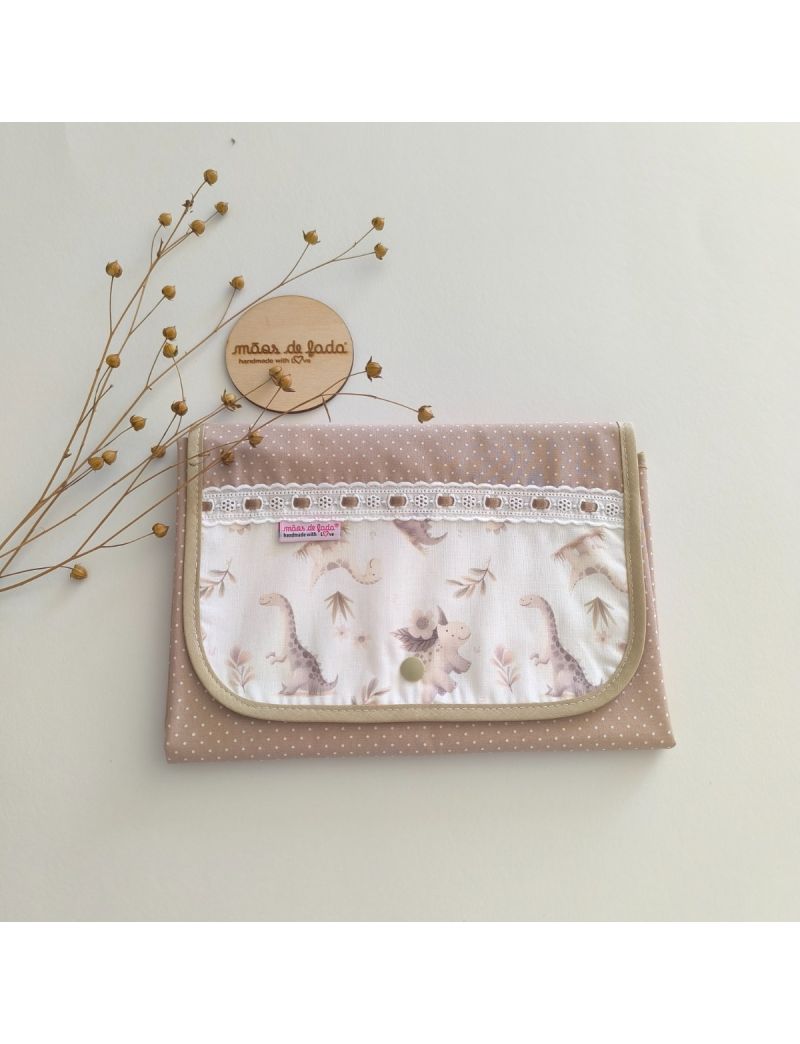 Muda fralda fechado com tecido bege com bolinhas brancas conjugado com tecido de dinoussauros em tons suaves. Com bordado inglês com fita bege