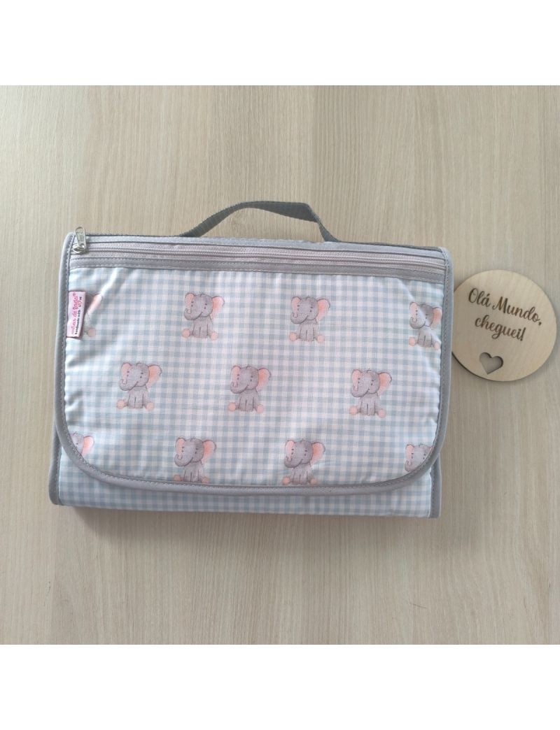 Bolsa multiusos fechada com uma bolsa frontal. Padrão de quadradinhos em verde água e branco com elefantes cinzentos. Fecho zíper e alça de mão cinzentos