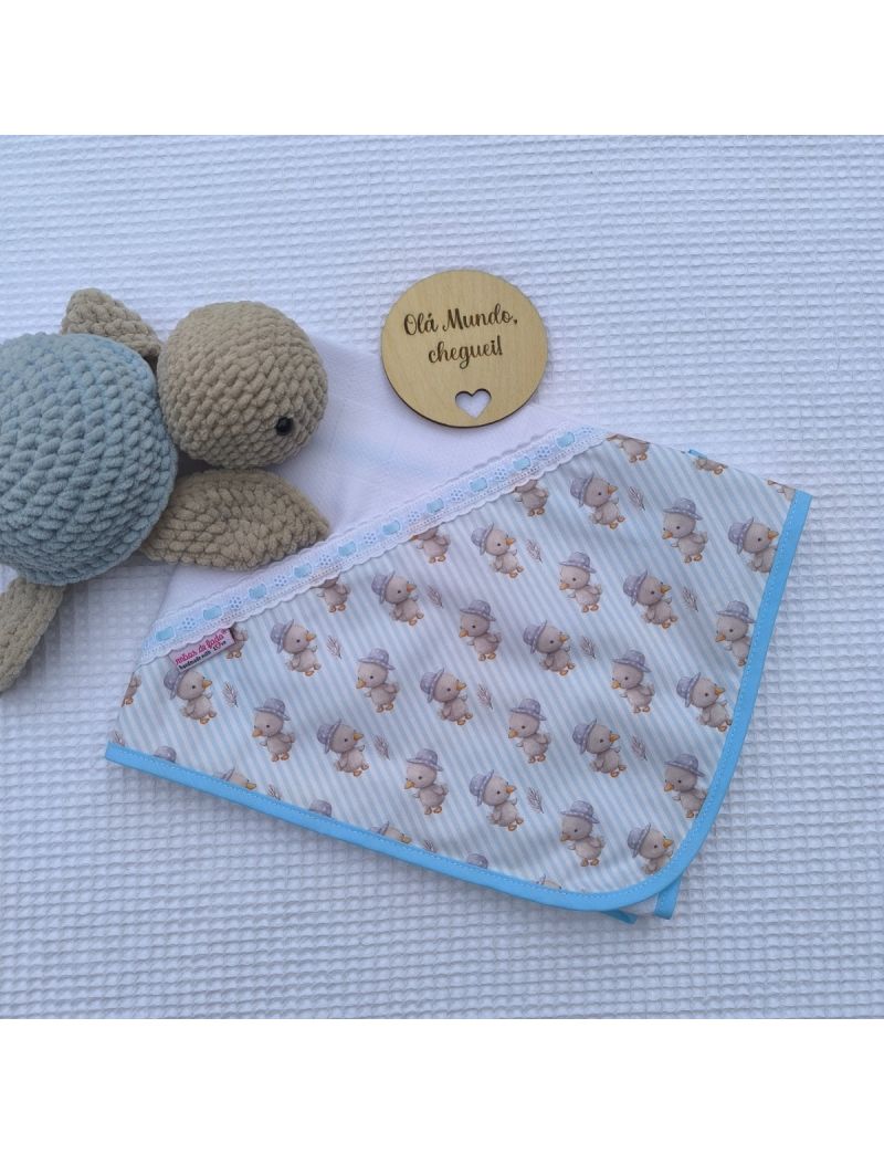 Fralda branca com canto com padrão de pintainhos. Bordado inglês com fita de cetim azyul clara. Tartaruga e placa decorativa com a descrição "Mãos de Fada "