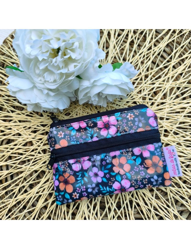 Porta-moedas pequeno em tecido plastificado impermeável, padrão floral em tons de azul, rosa e laranja, com duas bolsas e fecho, ideal para dinheiro e cartões. 