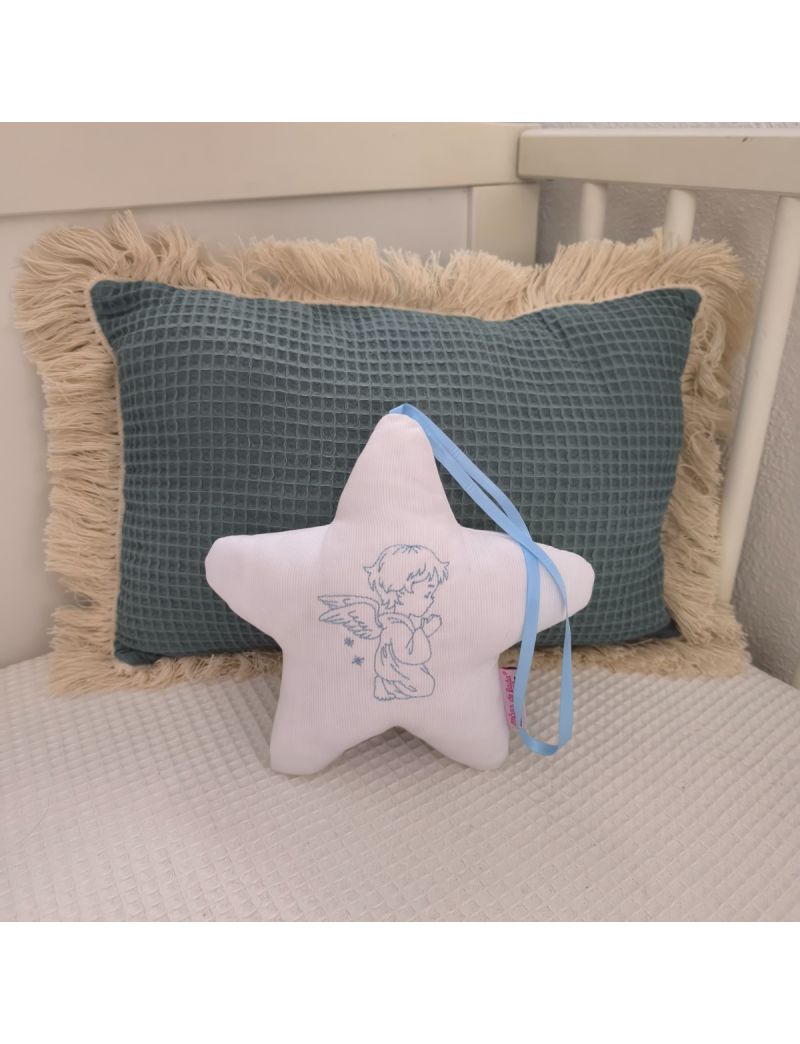 Estrela branca com anjo bordado a azul claro, fita azul claro e enchimento antialérgico, apoiada em almofadas decorativas num quarto de bebé