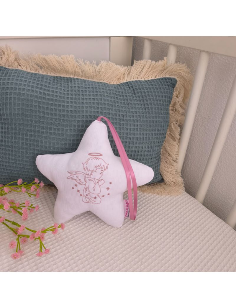 Estrela branca com anjo bordado a rosa velho, fita rosa velho e enchimento antialérgico, apoiada em almofadas decorativas num quarto de bebé