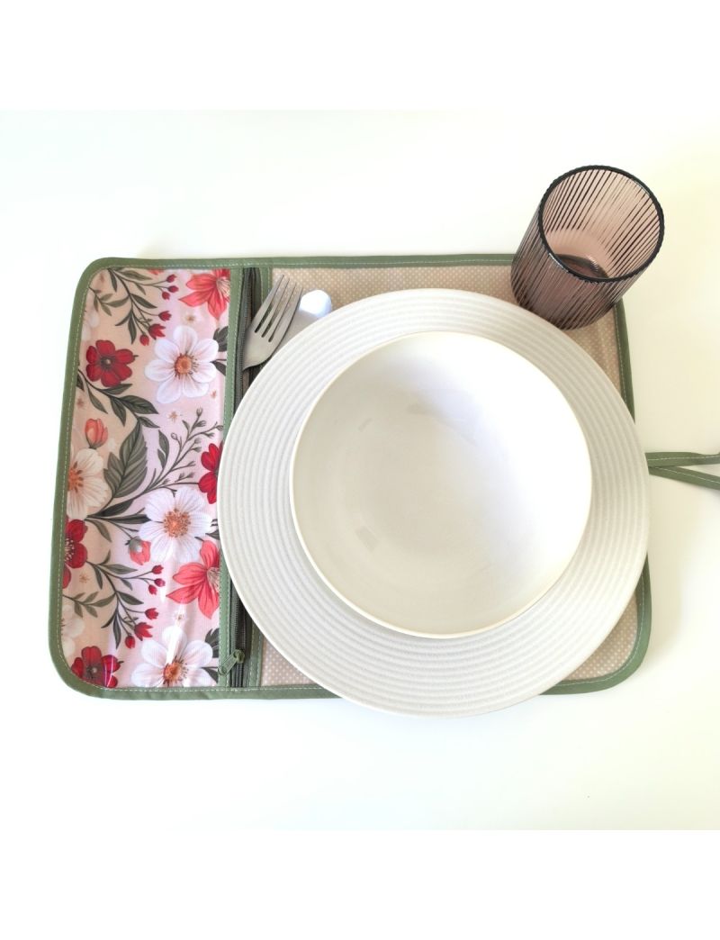 Individual aberto com padrão floral bordeaux, coral e branco na parte da bolsa para os talheres. Restante individual bege com bolinhas brancas.