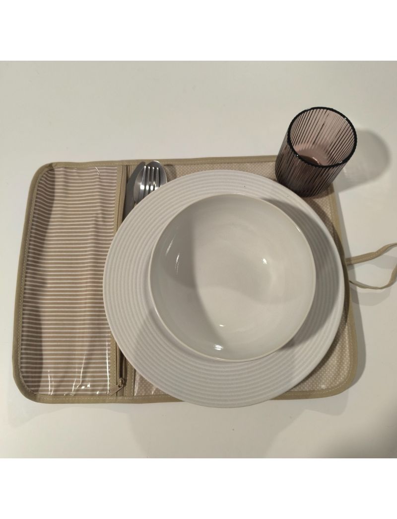 Individual aberto com padrão de riscas bege e brancas. Restante individual bege com bolinhas brancas. Prato, talheres e copo colocado no individual