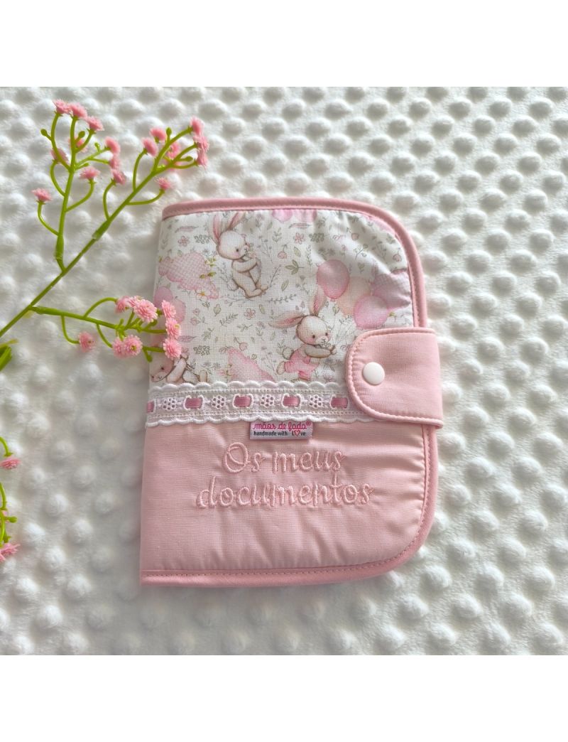 Porta documentos em formato livro fechado com padr&atilde;o de coelhos & bal&otilde;es um bordado ingl&ecirc;s com fita roda. Bordado rosa a dizer porta documentos  