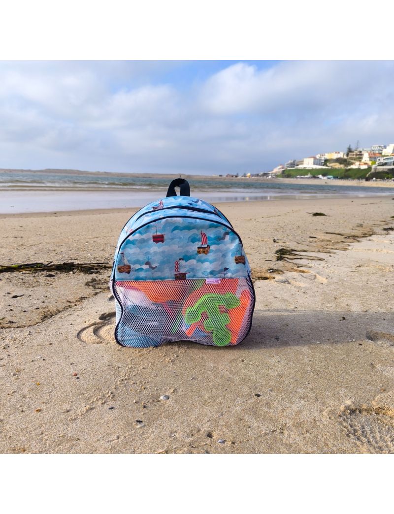 Mochila de praia com padr&atilde;o de barcos dos piratas. Fundo em azul com ondas do mar. Rede branca e al&ccedil;a em azul marinho