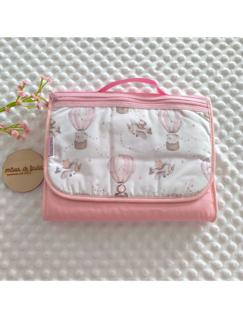 Bolsa multiusos fechada com uma bolsa frontal. Padr&atilde;o de bal&otilde;es de ar quente em tons de rosa e avi&otilde;es em tons de cinza e creme . Fecho z&iacute;per rosa