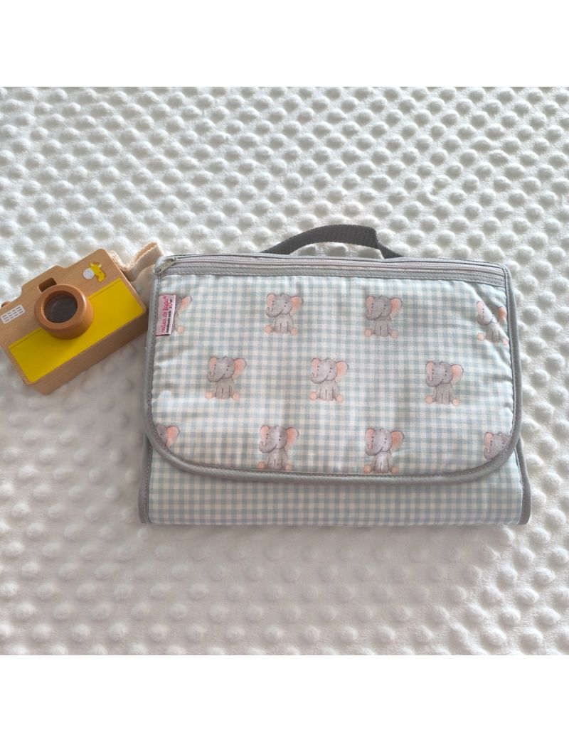 Bolsa multiusos fechada com uma bolsa frontal. Padr&atilde;o de quadradinhos em verde &aacute;gua e branco com elefantes cinzentos. Fecho z&iacute;per e al&ccedil;a de m&atilde;o cinzentos