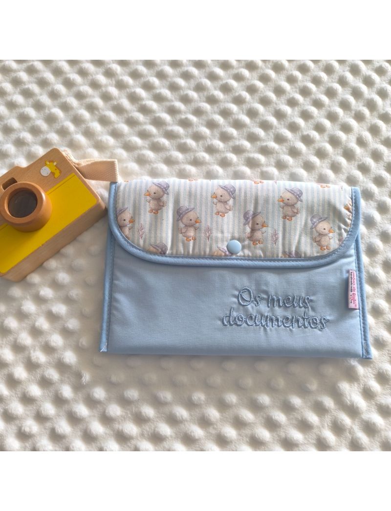 Porta documentos em formato envelope com padr&atilde;o azul liso com pala com padr&atilde;o de pintainhos, com a inscri&ccedil;&atilde;o "Os meus documentos" bordado a azul