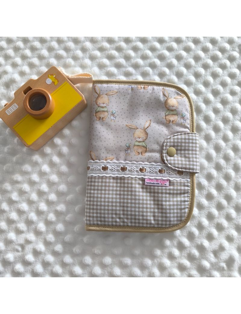 Porta documentos em formato livro com tecido com padr&atilde;o de ursinhos em tons de bege conjugado com tecido xadrez vicky em bege. Possui bordado ingl&ecirc;s com fita de cetim bege escuro