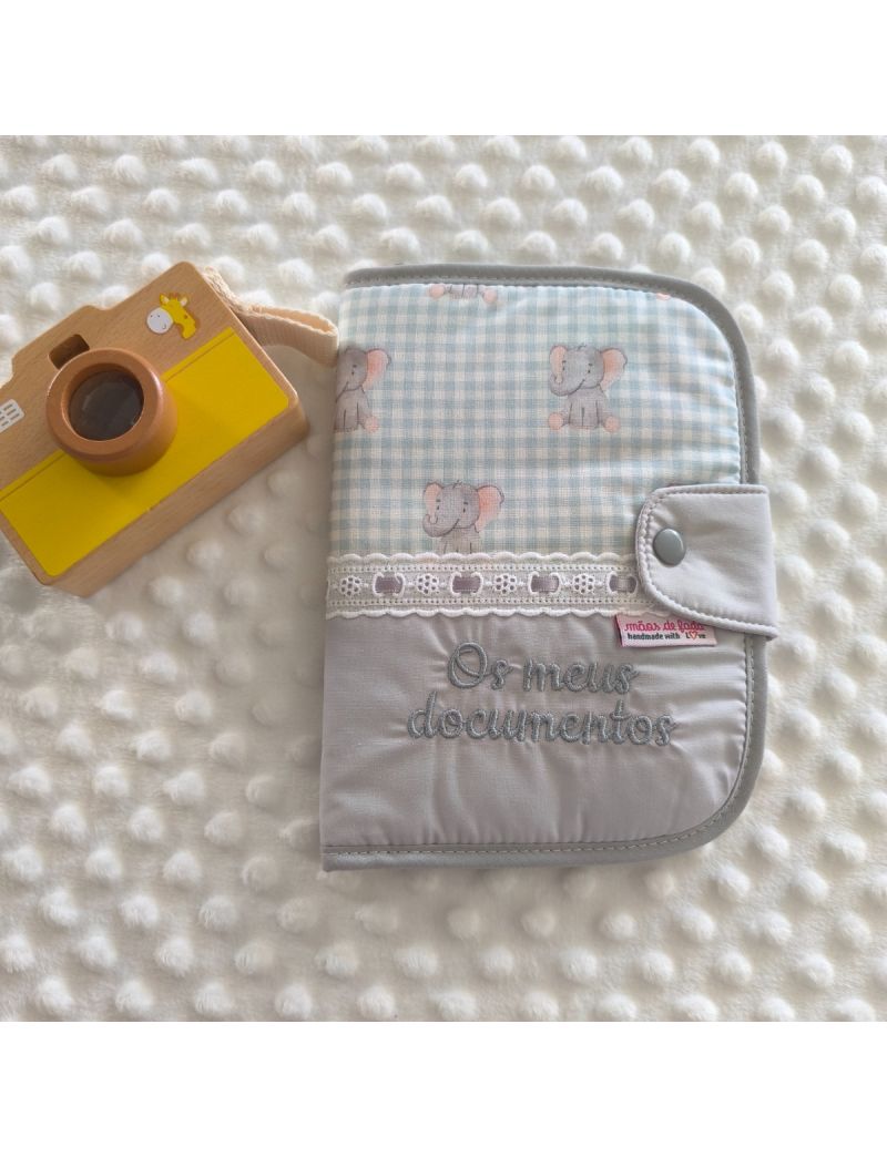 Porta documentos em formato livro com padr&atilde;o de elefantes em cima de tecido xafrez vichy verde &aacute;gua conjugado com tecido liso cinzento com a descri&ccedil;&atilde;o "Os meus documentos" a cinzento. Bordado ingl&ecirc;s na jun&ccedil;&atilde;o dos dois tecidos com fita de cetim cinza.