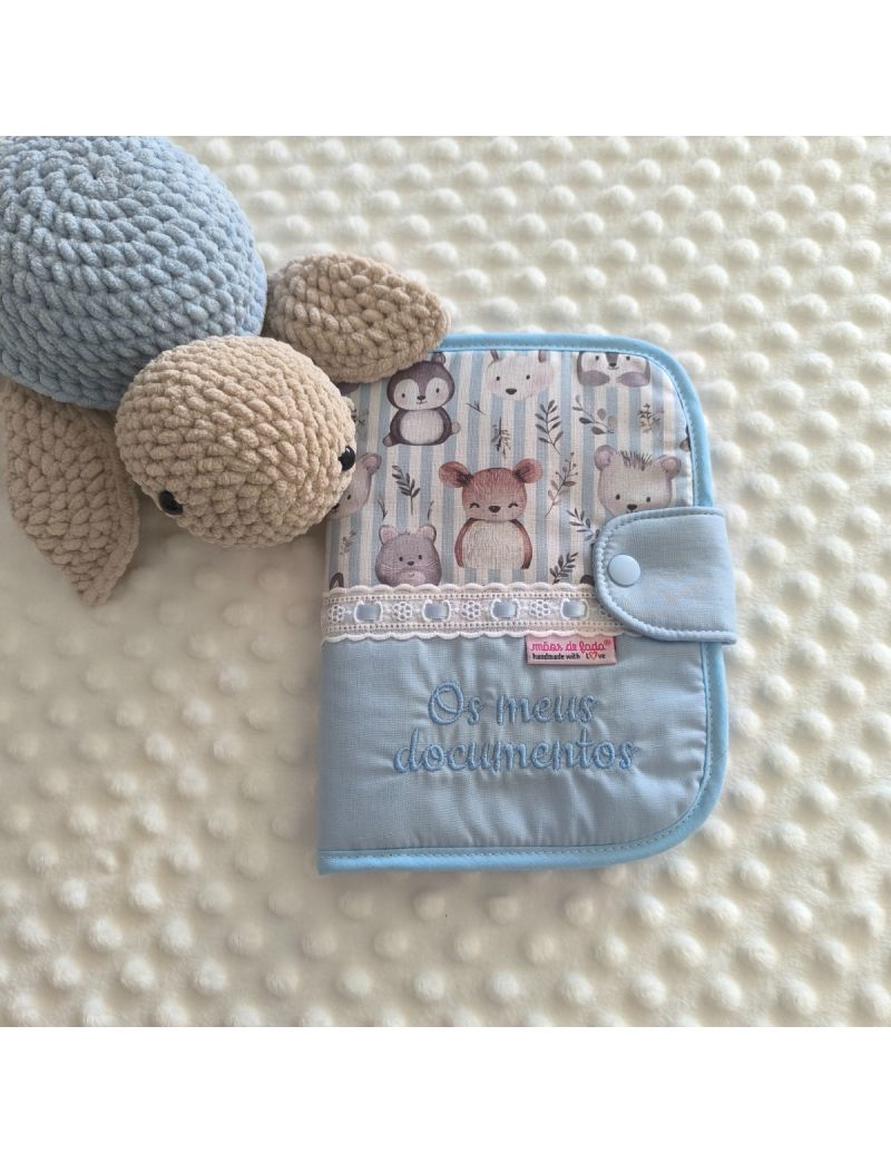 Porta documentos em formato livro  com padr&atilde;o de animais delicados na parte de cima e azul liso com a descri&ccedil;&atilde;o "Os meus documentos" em azul na parte de baixo. Bordado ingl&ecirc;s na jun&ccedil;&atilde;o dos dois tecidos. Tartaruga em amigurumi a decorar