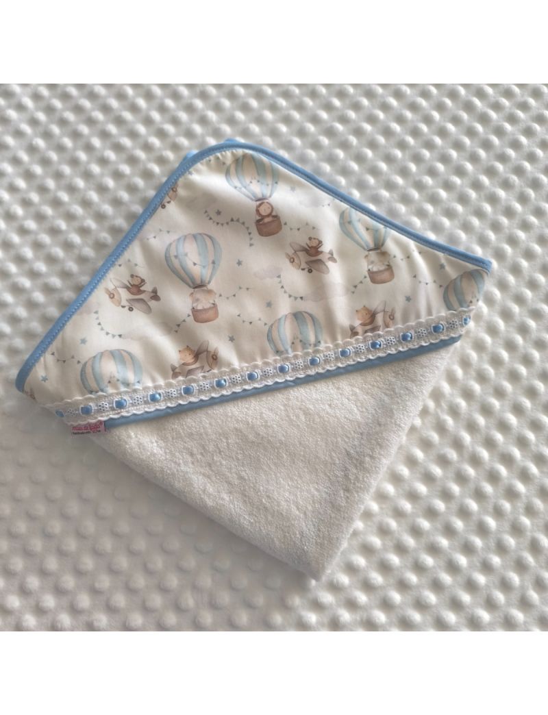 Toalha de banho em turco branco com capuz com padr&atilde;o de bal&otilde;es de ar quente e avi&otilde;es em tons suaves. Com bordado ingl&ecirc;s com fita azul