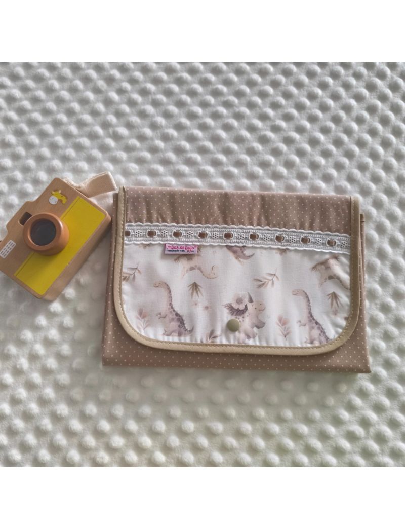 Muda fralda fechado com tecido bege com bolinhas brancas conjugado com tecido de dinoussauros em tons suaves. Com bordado ingl&ecirc;s com fita bege