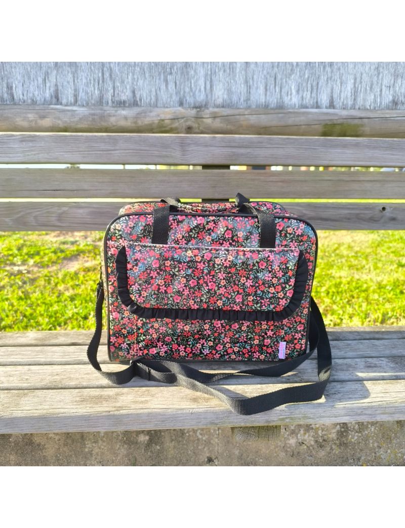 Lancheira tamanho XL com padr&atilde;o floral em tons salm&atilde;o e rosa em fundo preto. Al&ccedil;as de m&atilde;o refor&ccedil;adas, colocada sobre um banco de madeira