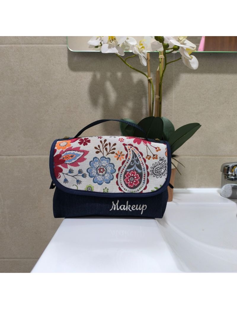 Bolsa de maquilhagem com padr&atilde;o floral, compacta e com al&ccedil;a verde, num ambiente de casa de banho.