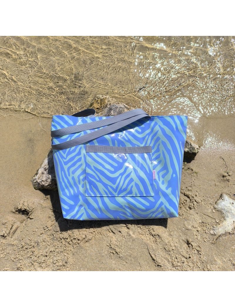 Saco de praia plastificado com padr&atilde;o de zebra em tons de roxo e verde. A mala tem um bolso exterior vis&iacute;vel e al&ccedil;as cinzentas