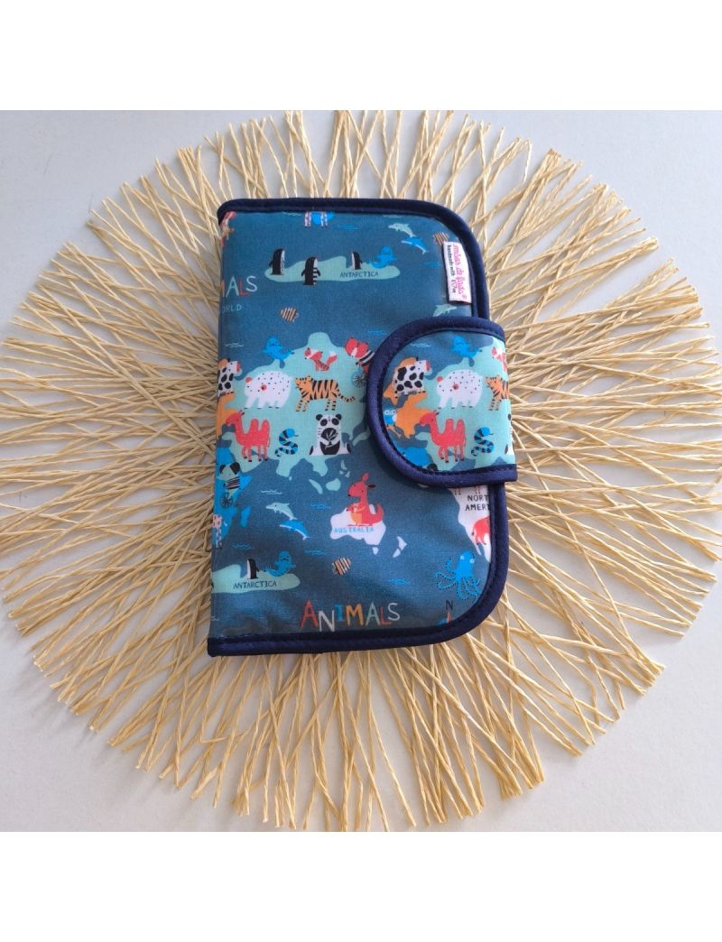 Bolsa de higiene plastificada com padr&atilde;o do mapa mundo com animai, em azul, fechada, com compartimentos para higiene oral, medica&ccedil;&atilde;o e produtos femininos.
