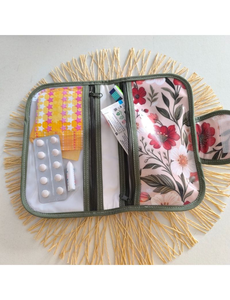 Bolsa de higiene plastificada com padr&atilde;o floral, aberta, com compartimentos para higiene oral, medica&ccedil;&atilde;o e produtos femininos.

