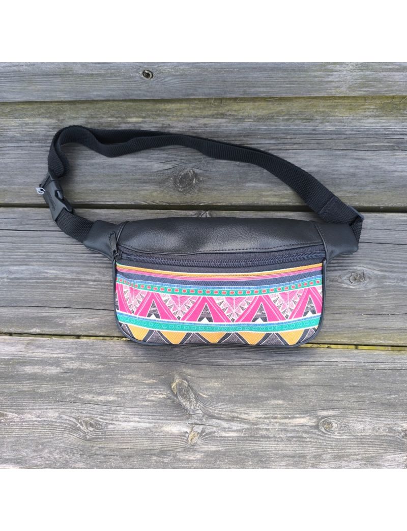 Bolsa de cintura em material sint&eacute;tico preto com um painel frontal em padr&atilde;o &eacute;tnico colorido, apresentando formas geom&eacute;tricas em rosa, amarelo, verde e azul. A bolsa possui um fecho de correr preto, al&ccedil;a de nylon ajust&aacute;vel com fivela de encaixe e est&aacute; pou