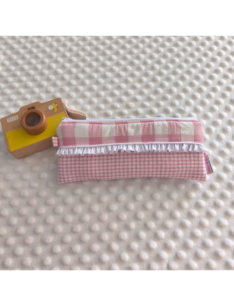 Estojo em tecido vichy rosa com folho decorativo e fecho de correr branco, pousado sobre uma manta branca texturada. O interior &eacute; imperme&aacute;vel e plastificado, ideal para guardar material escolar, artigos de higiene ou pequenos acess&oacute;rios.
